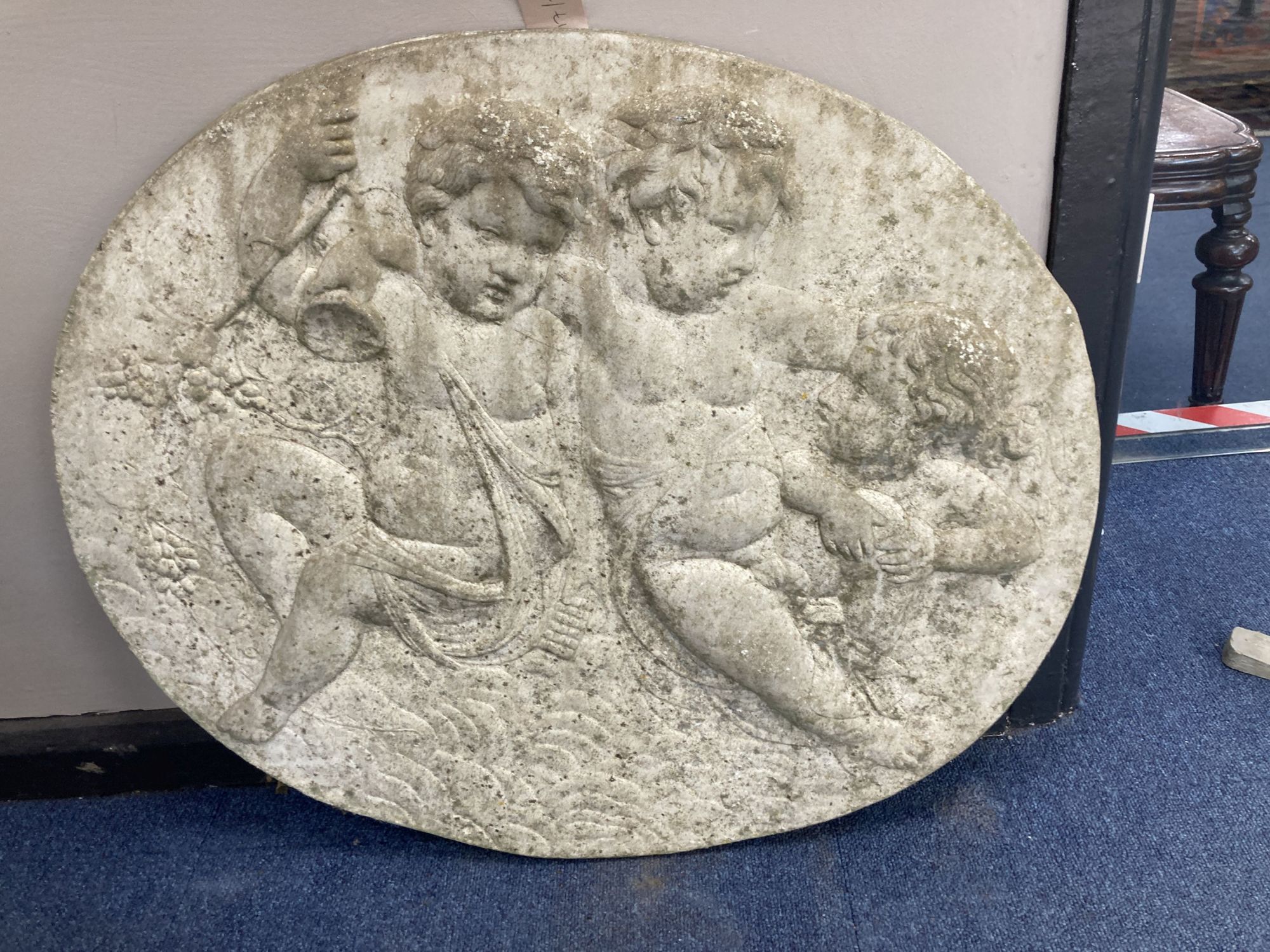 An oval reconstituted stone plaque, width 68cm, height 60cm